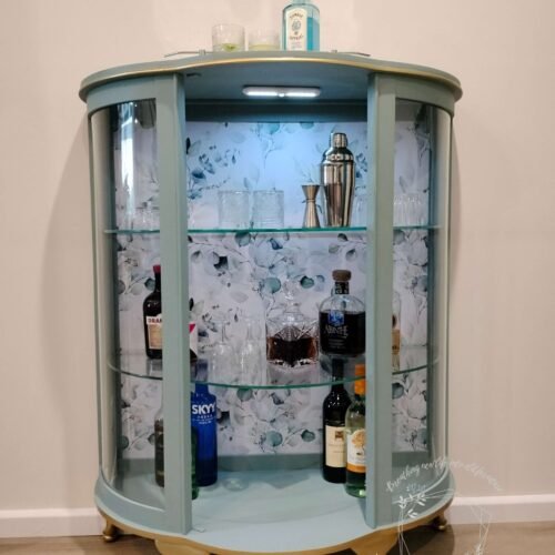 Cocktail cabinet in soft green painted with Australian eucalyptus wallpaper.